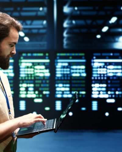 Developer checking event logs and diagnostic tools to identify server issues root cause. Programmer using laptop to check supercomputer operating system configuration settings
